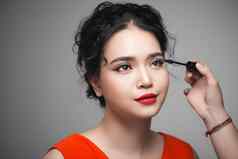 美丽的年轻的亚洲女人化妆睫毛膏睫毛