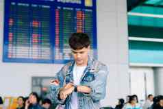 年轻的亚洲男人。站航空公司时间表触碰看