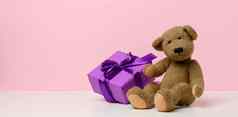 可爱的棕色（的）泰迪熊持有盒子包装纸红色的丝绸丝带白色表格奖祝贺你