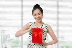 年轻的美丽的亚洲女人持有红色的礼物盒子