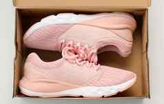 一对粉红色的纺织运动鞋开放棕色（的）纸盒子白色表格前视图