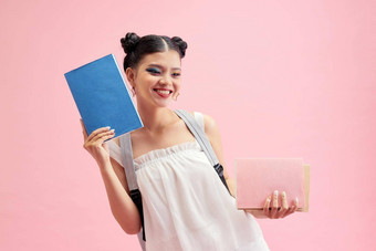 配置文件一边照片积极的女孩持有复制书走教室教训讲座图书馆孤立的粉红色的背景