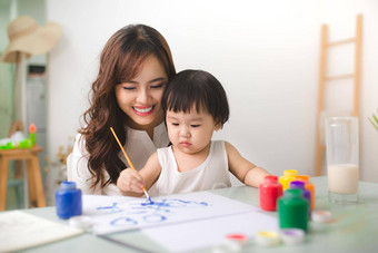 快乐家庭妈妈。女儿油漆亚洲女人帮助孩子女孩