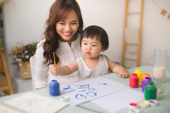 快乐家庭妈妈。女儿油漆亚洲女人帮助孩子女孩