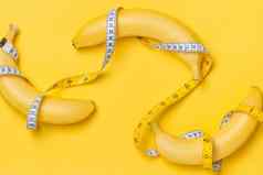 饮食健身健康概念提出了黄色的香蕉包装测量磁带孤立的黄色的纸背景