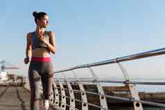 肖像年轻的健康的女人慢跑海边散步运行海深思熟虑的跑步者锻炼在户外培训