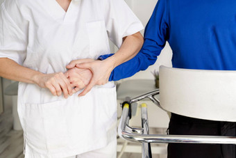 女护士照顾者持有病人手支持禁用病人坐轮椅医院年轻的医生护理员瘫痪病人