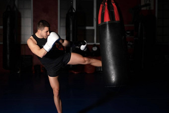 肌肉发达的英俊的跆拳道战斗机给有力的踢练习轮拳击袋
