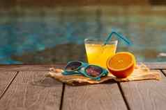 橙色新鲜的汁奶昔喝太阳镜游泳池