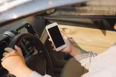 年轻的女司机触摸屏幕智能手机全球定位系统(gps)导航车