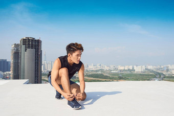 年轻的亚洲男人。领带体育运动鞋鞋带运行在户外