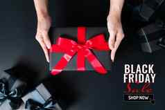 黑色的星期五出售女人手给礼物盒子黑色的背景