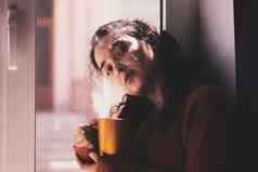 冷秋天天年轻的多种族女饮料咖啡舒适的窗台上