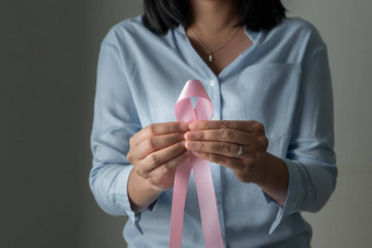 粉红色的徽章丝带女人手支持<strong>乳房癌症乳房癌症意识</strong>概念