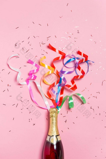 平躺庆祝活动香槟瓶色彩斑斓的聚会，派对飘带粉红色的背景