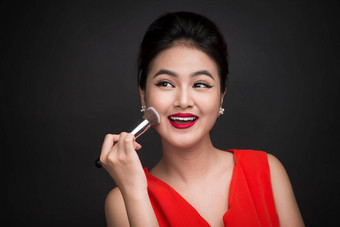 化妆品粉刷亚洲女人应用脸红的人脸颊完美的化妆红色的嘴唇
