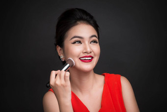 化妆品粉刷亚洲女人应用脸红的人脸颊完美的化妆红色的嘴唇