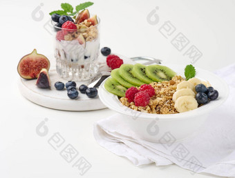 脆脆的白色轮板树莓猕猴桃香蕉玻璃加诺拉<strong>湿透</strong>了酸奶白色表格健康的早餐早....