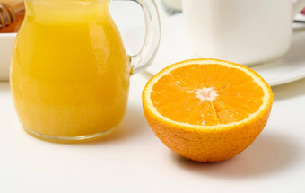 一半成熟的橙色新鲜挤压汁玻璃透明的玻璃水瓶白色表格