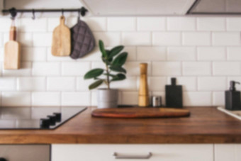 厨房黄铜餐具老板配件模糊厨房背景挂厨房白色瓷砖墙木桌面绿色植物厨房背景