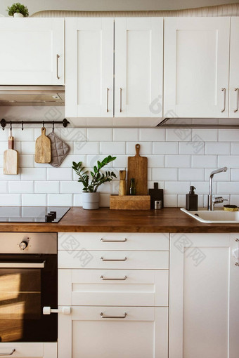 厨房黄铜餐具老板配件挂厨房白色瓷砖墙木桌面绿色植物厨房背景