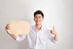 英俊的亚洲男人。经典衬衫持有演讲泡沫微笑站白色墙