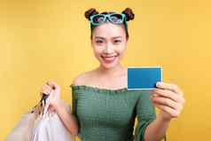 购物亚洲女人持有购物袋信贷卡黄色的背景
