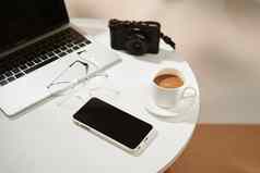 办公室桌子上移动电话咖啡杯移动PC相机眼镜