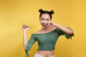 色彩斑斓的工作室肖像快乐年轻的亚洲女人耳机跳舞唱歌