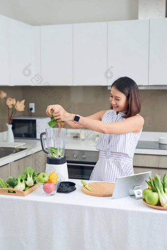 <strong>健康</strong>的亚洲女人享受使绿色蔬菜排毒净化绿色水果奶昔搅拌机厨房<strong>首页节</strong>食概念<strong>健康</strong>的生活方式