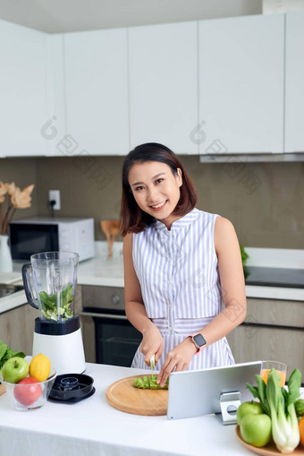 <strong>健康</strong>的亚洲女人享受使绿色蔬菜排毒净化绿色水果奶昔搅拌机厨房首页<strong>节</strong>食概念<strong>健康</strong>的生活方式
