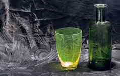 彩色的透明的绿色玻璃杯绿色玻璃瓶水喝表面反射黑色的背景
