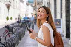 肖像微笑女大学学生智能手机走城市街