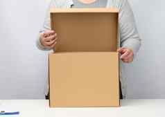 女人灰色的衣服站持有开放棕色（的）盒子白色背景移动发送交付货物