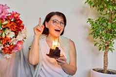 成熟的女人小生日蛋糕燃烧蜡烛