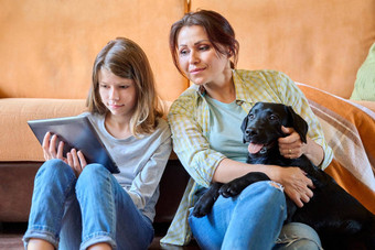 妈妈。女儿孩子拉布拉多小狗狗坐着沙发数字平板电脑
