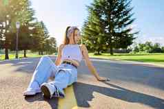 时尚时尚的十几岁的赶时髦的人女坐着路公园