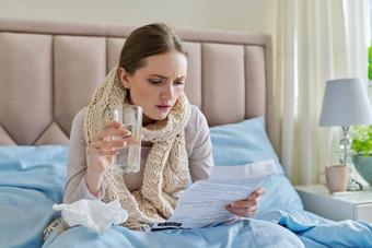 年轻的生病的女人首页床上女阅读指令药物治疗