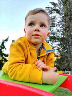 年轻的男孩橙色夹克享受骑马波动公园