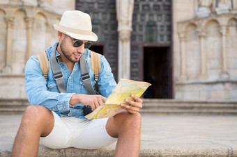 英俊的旅游男人。指出地图搜索方向目的地旅行概念旅行背包客旅游