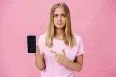 悲观的伤心可爱的年轻的女显示朋友负反馈项目互联网指出智能手机屏幕站有关心烦意乱粉红色的背景
