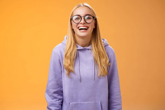有魅力的快乐的迷人的微笑女大学直学生眼镜紫色的舒适的连帽衫咧着嘴笑笑幸福的很高兴邀请手同学们站橙色背景