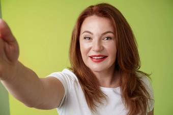 特写镜头快乐的热情的红色头发的人诱人的中年女人extand手臂相机采取自拍智能手机微笑广泛的摆姿势照片采取图片设备绿色背景