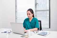 女医生工作医疗专业知识坐着桌子上前面移动PC