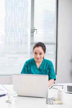 女医生工作医疗专业知识坐着桌子上前面移动PC