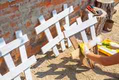 女人油漆栅栏花床上使绘画装饰栅栏花园
