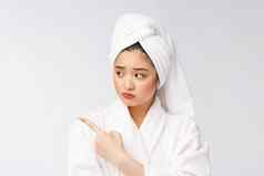 年轻的美丽的女人穿淋浴毛巾浴孤立的白色背景指出手指