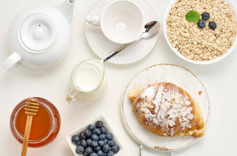 生燕麦片白色陶瓷板<strong>蓝莓</strong>蜂蜜白色表格早餐前视图