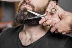 发型师手切割男人。胡子剪刀高质量美丽的照片概念