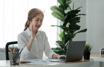 微笑年轻的女员工首页手波视频调用移动PC多样化的的同事们亚洲女人工人网络摄像头会议数字网络团队会议简报同事